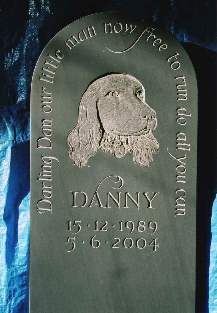 A pet dogÂ’s memorial stone with a carved image in the centre in Â‘Burlington StoneÂ’