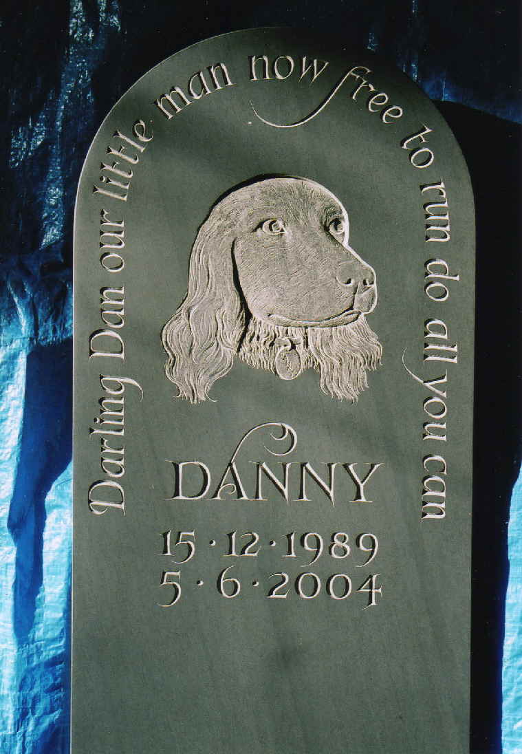 A pet dogs memorial stone with a carved image in the centre in Burlington Stone