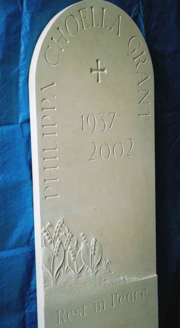 Rounded top headstone in portland stone with lilies in relief